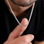 Hombre sosteniendo sobre su dedo una cadena Cuban Link de 3 mm en Plata .925, mostrando el grosor real de los eslabones cubanos y su proporción respecto a la mano.
