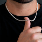 Hombre sosteniendo sobre su dedo una cadena cubana de 4 mm en Plata .925, mostrando el grosor real del tejido Cuban Link y su proporción respecto a la mano.